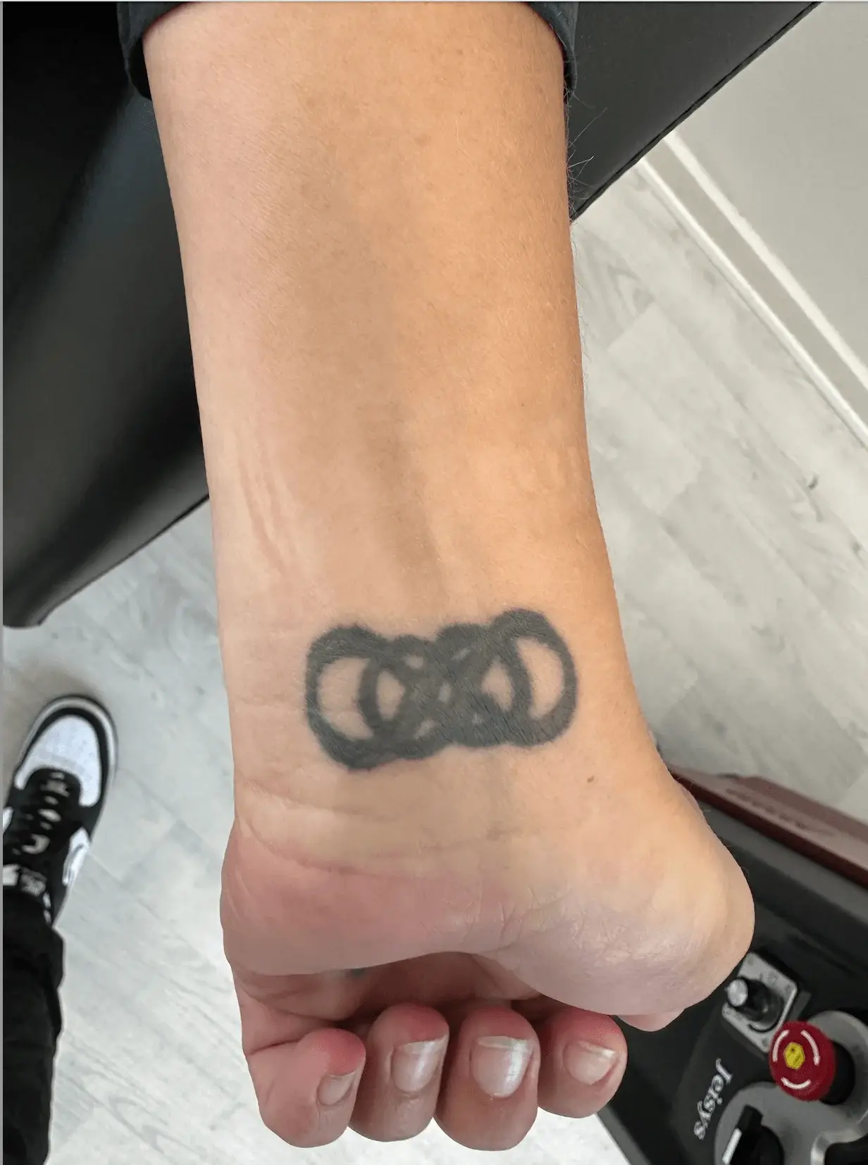 Sort tatovering med sammenflettede cirkler på håndled