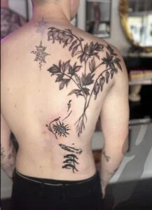 Ryg med detaljeret plantetatovering i sort blæk