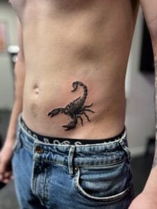 Sort skorpion tatovering på ribben