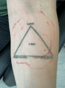 Trekantet tatovering med tekst på underarm